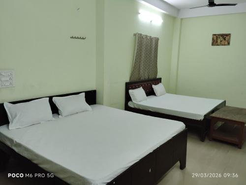 a room with two beds and a table in it at Hotel Shri Ram Palace in Rewa