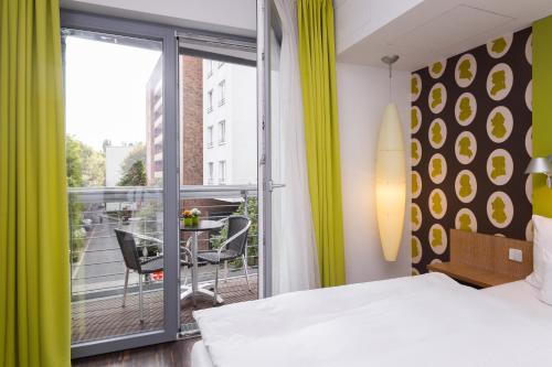 a bedroom with a bed and a balcony with a table at Grimm's Berlin Mitte in Berlin
