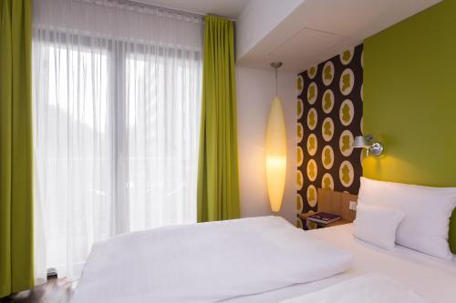 a bedroom with a white bed and a green wall at Grimm's Berlin Mitte in Berlin