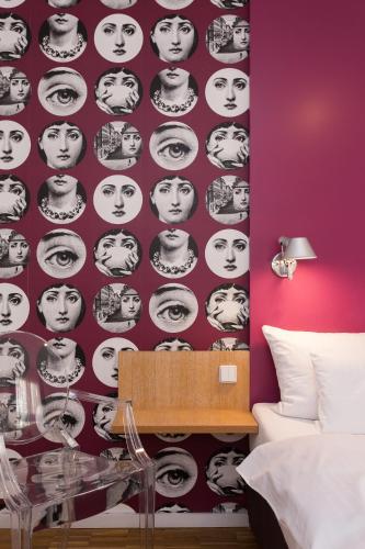 a bedroom with a purple wall with a black and white face wallpaper at Grimm's Berlin Mitte in Berlin