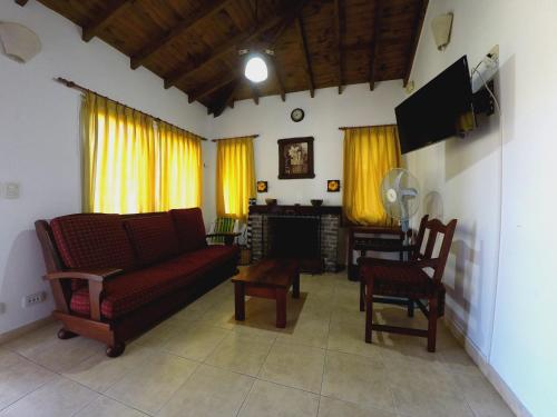uma sala de estar com um sofá e cadeiras e uma televisão em Cabañas Victoria em Mar de las Pampas