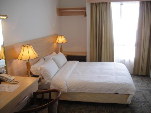 a hotel room with a bed and a desk with a desk at Prima Hotel Melaka in Melaka