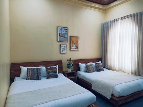 a bedroom with two beds and a window at a Hue Homestay in Hue