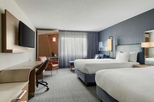 a hotel room with two beds and a desk at Courtyard Atlanta Suwanee in Suwanee