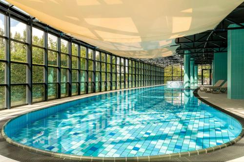 a large swimming pool with blue tiles in a building with windows at Residence Inn by Marriott Amsterdam Schiphol Airport in Badhoevedorp