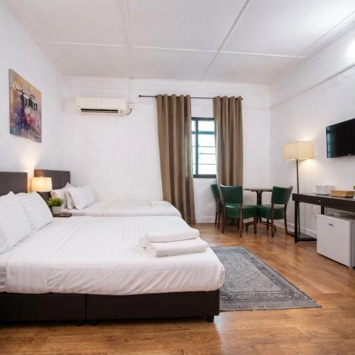 a bedroom with two beds and a table and chairs at Northern Cove Penang in Tanjung Bungah