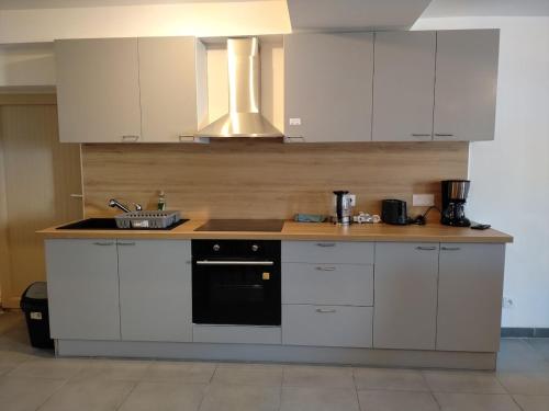 a kitchen with white cabinets and a sink at Ô Bon Goût in Bourges