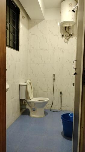 a bathroom with a toilet and a light on the wall at RKS Homestay Anex in Shillong