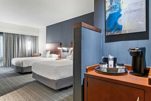 a hotel room with two beds and a table with a table at Courtyard by Marriott Clarksville in Clarksville