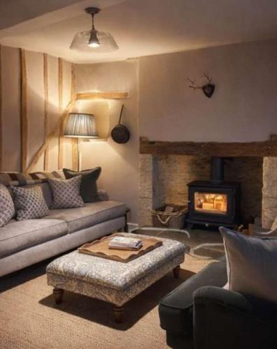 a living room with a couch and a fireplace at Jasmine Cottage, Upper Slaughter, Cotswolds in Cheltenham