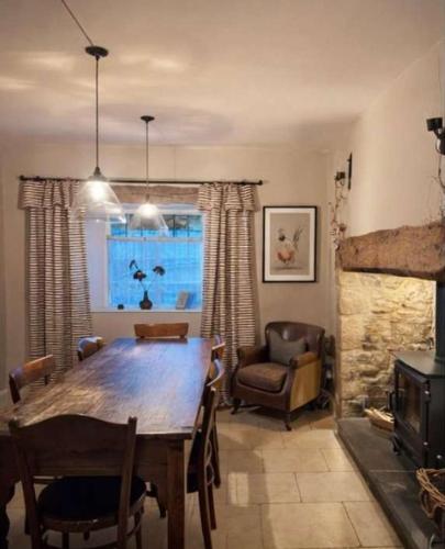 a dining room with a wooden table and a fireplace at Jasmine Cottage, Upper Slaughter, Cotswolds in Cheltenham