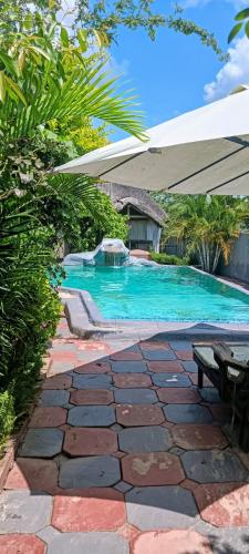 a swimming pool with an umbrella and a table at Newview bnb and spa in Thulamahashi