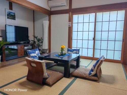 a living room with a table and chairs and a tv at Via Tsuru鶴苑1 minute from the station! in Izumi-Sano