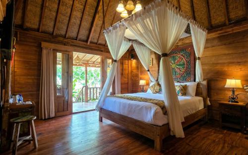 a bedroom with a canopy bed in a room with wooden walls at Sirya Farm House in Meliling