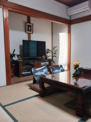 a living room with a coffee table and a tv at Via Tsuru鶴苑1 minute from the station! in Izumi-Sano