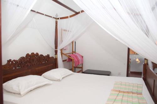 a bedroom with a white bed with a canopy at lionka guesthouse in Mirissa