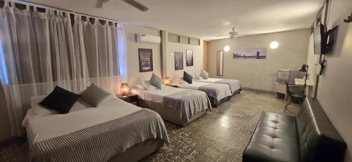 a hotel room with three beds and a couch at Casa Agena in Cartagena de Indias