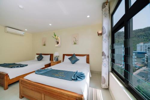 two beds in a room with a large window at Cat Ba Flora Hotel in Cat Ba