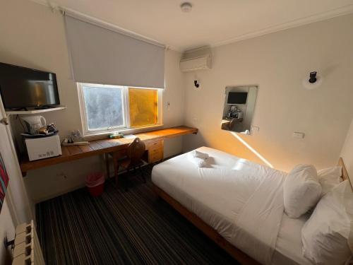 a hotel room with a bed and a desk and a television at Bunkhouse Motel Cooma in Cooma