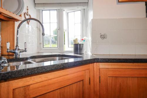 a kitchen with a sink and a window at Ivy Cottage in Tintagel