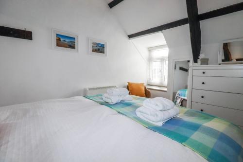 a bedroom with a white bed with towels on it at Ivy Cottage in Tintagel