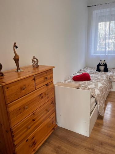 a bedroom with a bed and a dresser and a stuffed animal at Ladislaus Garden Suites in Cegléd