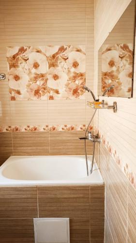 a bath tub in a bathroom with flowers on the wall at Дарина in Chornomorsk