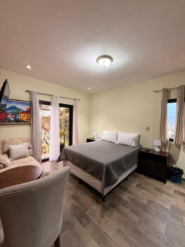 a bedroom with a bed and a couch and windows at Hotel y Restaurante Vista Verde in Santa Lucía Milpas Altas
