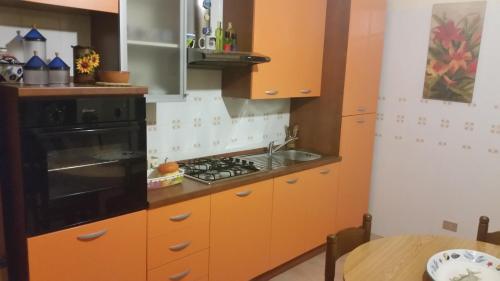 una cucina con armadi arancioni e piano cottura. di Cornino Relax a Custonaci