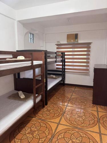 a room with bunk beds and a tile floor at Mabel's Garden Stay in Puerto Galera