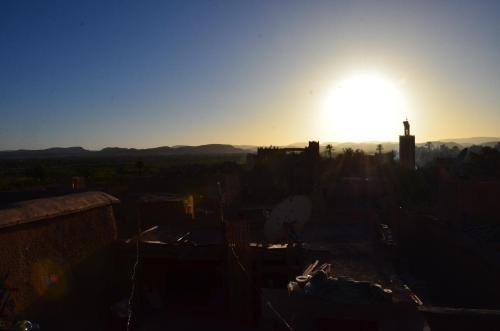 a view of the sun setting over a city at Maison d'hôtes Dar El Nath in Ouarzazate
