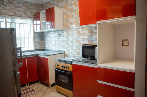 a kitchen with red cabinets and a stove top oven at Spacious 3-Bedroom in Central Ikeja in Ikeja