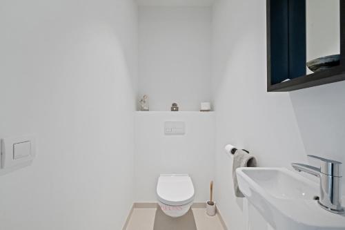 a white bathroom with a toilet and a sink at Zilt 15 in Ostend
