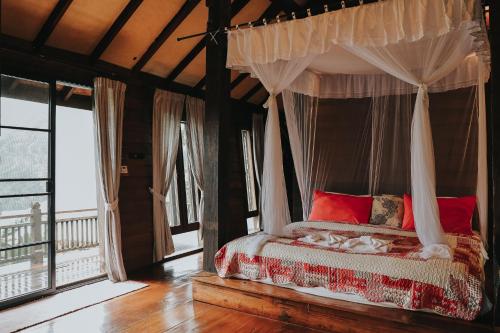 a bedroom with a canopy bed with red pillows at Baan Mon Muan in Mon Jam