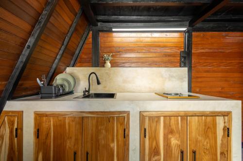 a kitchen with a sink and wooden cabinets at Brisa Lofts Uluwatu in Uluwatu