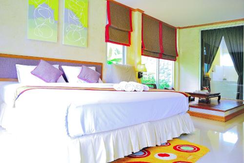 a bedroom with a large bed with white sheets and purple pillows at Moosiyard Hometel Khaoyai in Mu Si