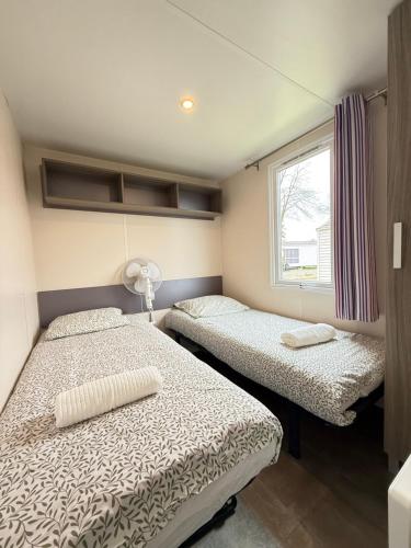 two beds in a small room with a window at Le G9 - Bungalow lumineux pour 4 avec TV in Boofzheim