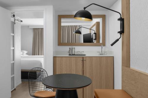 a kitchen with a table and a mirror and a bed at Sheraton Suites Fort Lauderdale at Cypress Creek in Fort Lauderdale