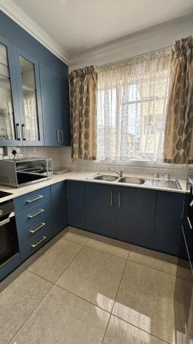 a kitchen with blue cabinets and a sink and a window at Two Sixty Nine in Gqeberha