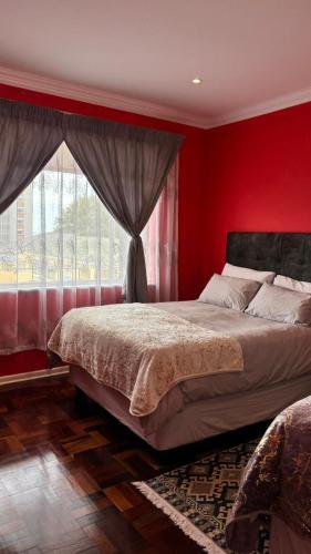 a bedroom with red walls and a bed with a window at Two Sixty Nine in Gqeberha