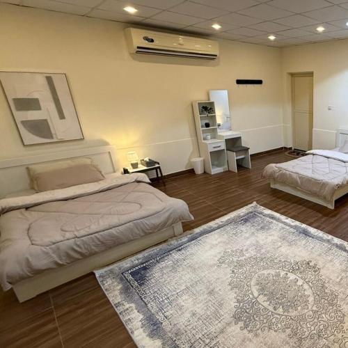 a large room with two beds and a rug at safeer farm in Qūr