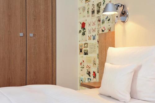 a bedroom with a bed with white sheets and a lamp at Grimm's Berlin Mitte in Berlin