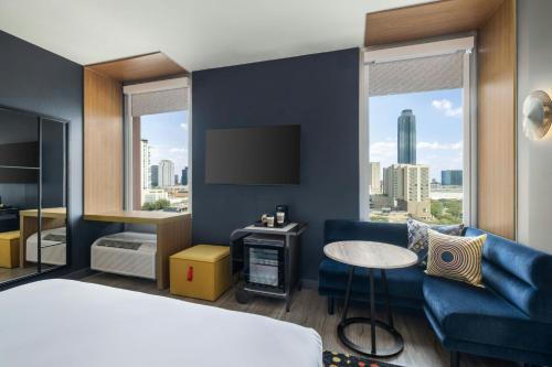 a hotel room with a bed and a couch and a tv at Aloft by Marriott Houston by the Galleria in Houston