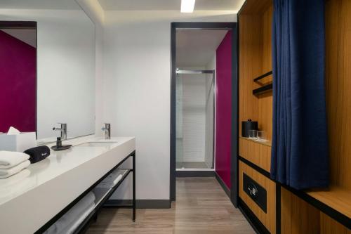 a bathroom with a sink and a mirror at Aloft by Marriott Houston by the Galleria in Houston