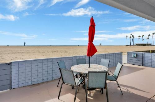 a table with chairs and an umbrella on the beach at Value Beachfront withLarge Patio On The Bike Path apts in Newport Beach
