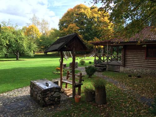 a bench and an umbrella in front of a cabin at Sodyba Duburiai in Ukmergė