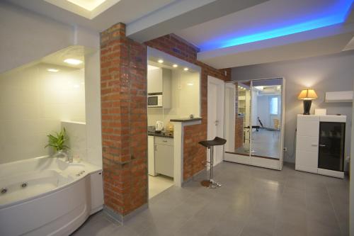 een badkamer met een wit bad en een bakstenen pilaar bij Apartment Hermes in Belgrado