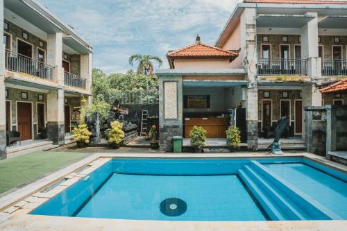 a swimming pool in front of a house at Santhi Graha Guest House in Legian