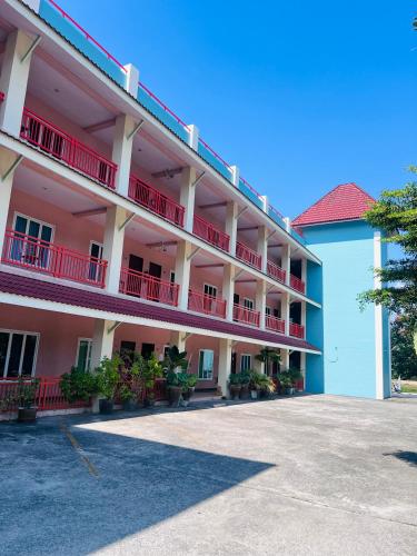 an apartment building with red balconies and a parking lot at โรงแรมสิริพรชัย in Takua Pa