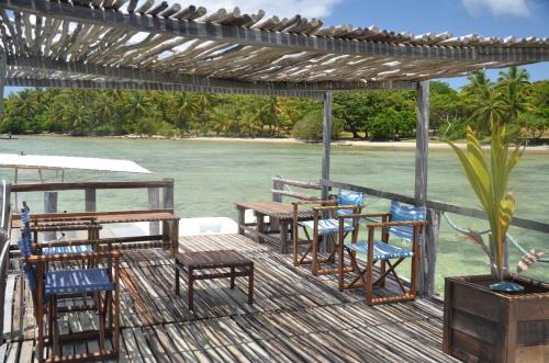 a deck with chairs and tables on the water at Boraha Village Ecolodge in Sainte Marie